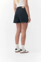 Short de denim negro de tiro alto, con bolsillos laterales y traseros, y cierre frontal con botón y cremallera.