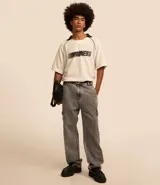 Pantalón de jean modelo baggy con bolsillos cargo laterales, cintura con trabillas y cierre frontal con botón y cremallera.