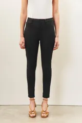 Pantalón de jean negro de corte skinny y tiro alto, confeccionado en gabardina con elastano y recubrimiento que simula cuero.