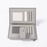 Billetera de cuero sintético color gris con diseño trenzado y cierre de solapa con botón a presión. Cuenta con compartimento con cierre superior y tarjetero frontal.