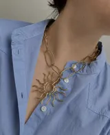 Collar de cadena de eslabones irregulares con un dije central grande en forma de sol estilizado, realizado en bronce.