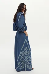 Jean wide leg de denim azul con elástico en la cintura, cordón ajustable y bordados decorativos en los laterales.