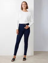 Jean skinny de tiro alto, color azul oscuro, con pretina con pasadores, botón y cierre. Delantera con tres bolsillos, dos simulados y uno aplicado. Trasera con bolsillos aplicados.