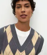 Chaleco de punto corto con diseño de rombos en tonos gris y beige. Presenta escote en V, sisas amplias y terminaciones acanaladas en el ruedo y el cuello.