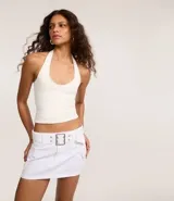 Minifalda blanca de sarga con cintura baja, trabillas, bolsillos cargo y cinturón con hebilla cuadrada metálica.