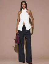 Top blanco sin mangas con cuello halter cruzado, espalda descubierta y abertura frontal.