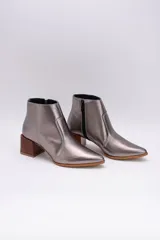 Botas cortas de cuero color beige, con punta fina y cierre lateral. Tienen un taco cuadrado de madera.