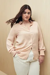 Camisa color café con textura sutil, cuello clásico, botones forrados a tono y mangas largas con puños fruncidos.