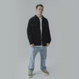 Campera negra de pana con cuello camisero, cierre con botones a presión, dos bolsillos de parche en el pecho y corte recto.