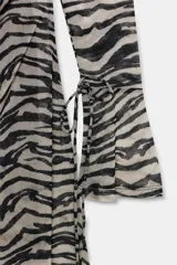 Vestido corto de tul con estampado animal print tipo cebra, escote barco y mangas largas acampanadas con lazadas ajustables. Cuenta con espalda abierta con detalle de lazada superior.