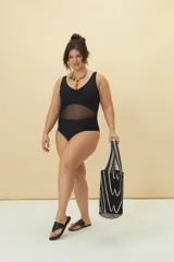 Malla enteriza negra con escote cruzado y panel central de tul transparente en la cintura.