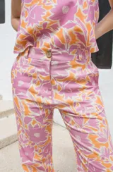 Pantalón de tiro medio con corte semi-oxford y tajos en el ruedo. Presenta un estampado floral en tonos rosados y naranjas.
