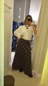 Pollera larga de corte recto con estampado de cuadros en tonos azul, gris y marrón. Presenta un diseño de tiro alto y cierre lateral.