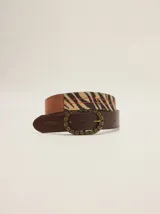 Cinto ancho de cuero marrón con hebilla ovalada metálica grabada y aplique de tela con estampado de animal print tipo cebra.