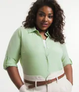 Camisa de tricolina color verde claro, con cuello inglés, mangas largas con trabilla para sujetar y botones delanteros.