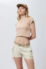 Top corto de manga corta, color beige claro, con cuello redondo y costuras verticales decorativas en el frente.