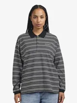 Remera polo de manga larga con diseño a rayas horizontales en tonos gris, negro y blanco. Presenta cuello clásico en color negro, cierre frontal con botones y logo bordado en el pecho.