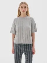 Remera de punto color gris claro, de manga corta, cuello redondo y diseño de trenzas verticales.