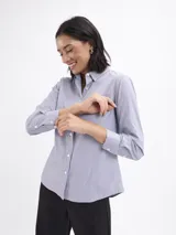 Camisa de corte clásico con estampado de rayas finas verticales, cuello camisero, cierre frontal con botones y mangas largas con puños abotonados.