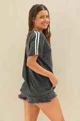 Remera negra con efecto acid wash y corte oversize, de manga corta con dos líneas blancas en los hombros.