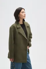 Chaqueta de corte holgado en color negro, con cuello solapa, cierre frontal con botones y bolsillos laterales.