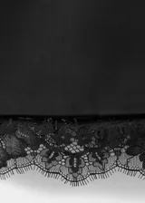 Vestido corto entallado de color negro, con cuello redondo y manga larga. Presenta un diseño de espalda abierta con tiras y un delicado detalle de encaje en el bajo. Incluye forro interior y cierre de cremallera en la parte posterior.