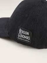 Gorra tipo baseball confeccionada en pana color azul marino, con parche rectangular lateral que incluye el logo de la marca Benson & Thomas.