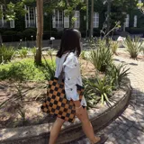 Bolso tipo tote de cuero trenzado a mano con diseño de damero en colores marrón y beige. Cuenta con doble asa trenzada y forro interior.