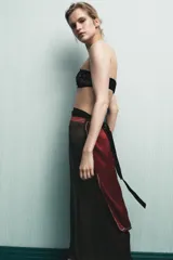 Pareo tipo pañuelo de viscosa con diseño cruzado y cierre mediante lazada en la cintura. Presenta un estampado de lunares pequeños sobre fondo bordó y un panel lateral en color verde oscuro con microestampado, ambos con bordes definidos.