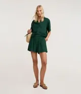 Short femenino de estilo runner, color verde oscuro, confeccionado en viscolino (mezcla de lino y viscosa). Presenta cintura elástica con botón y bolsillos laterales.