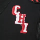 Campera deportiva negra con cierre frontal, cuello, puños y ruedo acanalados con rayas rojas y blancas. Presenta el logo de los Chicago Bulls en el pecho y letras bordadas en la manga izquierda.