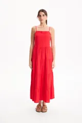 Vestido largo color blanco, confeccionado en lino, con tiras finas regulables, escote recto y falda amplia de corte acampanado con volados escalonados.