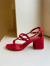Sandalias rojas de cuero nobuk con tiras finas y detalle de nudos en el empeine. Ajuste con pulsera al tobillo y taco cuadrado de 7 cm.