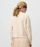 Cardigan de algodón color beige con escote en V, cierre frontal con botones y puños y cintura acanalados.