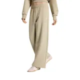Pantalón de jogging Adidas modelo Soft Lux de color beige, con cintura elástica fruncida, corte holgado de pernera recta y pequeño logo bordado en la pierna izquierda.