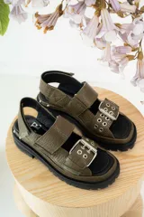 Sandalias negras de cuero con diseño de plataforma dentada, tiras ajustables con hebillas metálicas y detalle de tachas plateadas en el lateral de la suela.