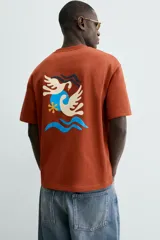 Camiseta de manga corta y cuello redondo, color terracota, con un pequeño bordado de una flor amarilla y la inscripción "Abstract Harmony" en el pecho.