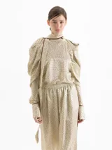 Top de seda con estampado floral pequeño, cuello alto con lazo integrado, mangas largas abullonadas con frunces en los hombros y puños camiseros con botones. Presenta detalles de ribete en color contrastante.