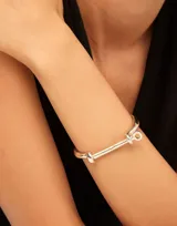 Pulsera rígida de diseño minimalista con cierre tipo grillete, fabricada en aleación de metales con baño de oro de 18k.