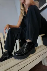 Borcego de cuero color marrón oscuro con acabado desgastado en la puntera. Presenta un diseño de caña corta con cierre lateral y dos tiras ajustables con velcro en el empeine. Cuenta con una suela de goma robusta tipo tractor.