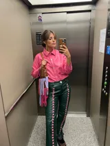 Camisa de cuero color rosado, con cuello clásico, cierre frontal de botones y mangas largas con puños rectos.