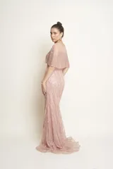 Vestido largo de tul color rosado, con sobrecapa corta y diseño entallado, íntegramente bordado con perlas y piedras.