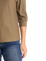 Blusa de tejido acanalado con cuello redondo y mangas tres cuartos. Presenta detalle de tachas metálicas a lo largo de los hombros y mangas, con puños elastizados.