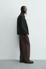 Pantalón jogger de algodón color marrón oscuro, de corte relajado y pierna ancha. Presenta cintura elástica con cordón ajustable y bolsillos laterales y uno trasero de plastrón.