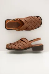 Sandalias de cuero marrón con diseño de tiras trenzadas tipo huarache, punta cuadrada y suela plana con taco bajo.