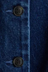 Chaleco de denim azul oscuro, sin mangas, con escote redondo y cierre frontal de botones oscuros. Presenta costuras moldeadoras y un diseño con peplum en la parte inferior.