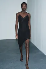 Vestido midi de estilo lencero confeccionado en viscosa, con escote en pico, tirantes finos y detalle de encaje a tono. Presenta un diseño con bajo asimétrico.
