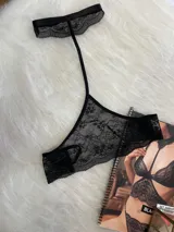 Accesorio tipo collarín de encaje negro con diseño floral, cuenta con una banda ajustable para el cuello y una tira que desciende hacia el pecho.