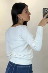 Buzo de hilo gris con textura acanalada, escote en V y cierre frontal con botones pequeños.