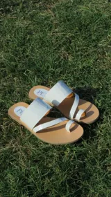 Sandalias bajas con base color suela y tiras de cuero sintético blanco con textura tipo cocodrilo.